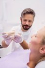 Dentista che mostra il modello di protesi al paziente in clinica — Foto stock