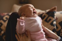 Nahaufnahme einer Mutter, die weinendes Baby im heimischen Wohnzimmer tröstet — Stockfoto