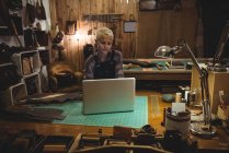 Зрелая ремесленница с помощью ноутбука в мастерской — стоковое фото