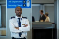 Портрет співробітника служби безпеки аеропорту, що стоїть зі зброєю, перетнутою в терміналі аеропорту — стокове фото