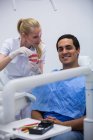 Dentista che mostra una serie di denti modello al paziente in clinica — Foto stock