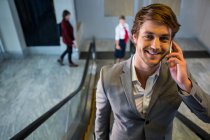 Бізнесмен на ескалаторі розмовляє на мобільному телефоні в аеропорту — стокове фото