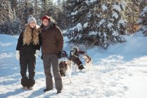 Portrait of smiling mushers standing with sledge on a snowy landscape — Stock Photo