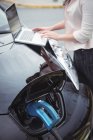 Seção média da mulher usando laptop enquanto carrega carro elétrico na rua — Fotografia de Stock