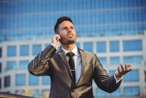 Businessman talking on the mobile phone near office building — Stock Photo