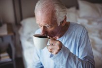 Старший мужчина пьет кофе в спальне дома — стоковое фото