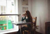 Рыжая женщина пьет кофе в ресторане — стоковое фото