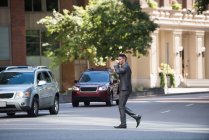 Uomo d'affari che prende un caffè mentre attraversa la strada alla luce del giorno — Foto stock