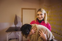 Ritratto di donna che tiene il cane in asciugamano al centro di cura del cane — Foto stock