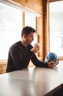 Homem em seu telefone bebendo café na estação de esqui — Fotografia de Stock
