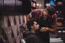 Kundin rasiert sich Bart mit Trimmer im Friseurladen — Stockfoto