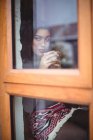 Mujer pensativa tomando una taza de café en la cafetería - foto de stock