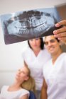 Dentistas discutiendo sobre informe de rayos X dentales en clínica - foto de stock