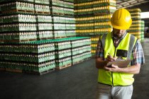 Male worker writing on clipboard in warehouse — Stock Photo