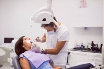 Стоматолог вивчає жіночі зуби пацієнта в клініці — стокове фото