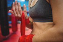 Mittelteil einer Boxerin mit rotem Riemen am Handgelenk im Fitnessstudio — Stockfoto