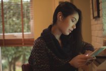 Frau nutzt digitales Tablet am Küchentisch in der Wohnung — Stockfoto