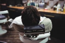 Client relaxing on chair in barber shop, rear view — Stock Photo
