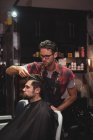 Cabeleireiro penteando o cabelo do cliente na barbearia — Fotografia de Stock