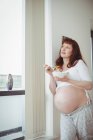 Mulher grávida cuidadosa ter salada perto da janela em casa — Fotografia de Stock