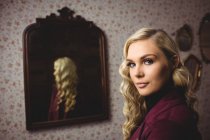 Portrait of a beautiful woman standing in front of mirror — Stock Photo
