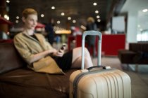 Donna d'affari che utilizza il telefono cellulare in sala d'attesa presso il terminal dell'aeroporto — Foto stock