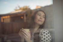 Mulher atenciosa tendo xícara de café perto da janela no café — Fotografia de Stock