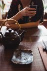 Partie médiane de la femme assise à table et prenant le thé — Photo de stock