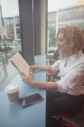 Pensativa mujer de negocios leyendo el periódico en el mostrador en la cafetería - foto de stock