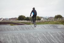 Vue arrière du cycliste à vélo BMX dans le skatepark — Photo de stock