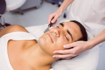 Dermatólogo realizando depilación láser en la cara del paciente en la clínica - foto de stock