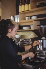 Cameriera che tiene portafilter riempito con caffè macinato in caffè — Foto stock