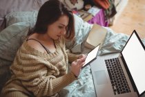 Красива жінка, використовуючи цифровий планшет і ноутбук на ліжку у себе вдома — стокове фото