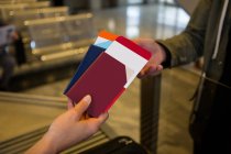 Asistente de facturación de las manos de la aerolínea que entrega pasaportes a los pasajeros en el mostrador de facturación del aeropuerto - foto de stock