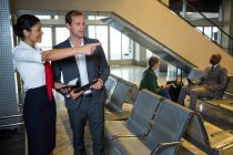 Mitarbeiterin zeigt Geschäftsmann am Flughafen-Terminal die Richtung — Stockfoto