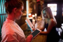 Офіціантка за допомогою цифрового планшета в барі — стокове фото