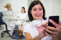 Жінка-лікар, що використовує мобільний телефон у клініці — стокове фото