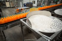 Vue grand angle des bouteilles de boissons froides orange sur la chaîne de production en usine — Photo de stock