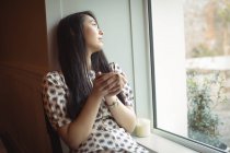 Frau trinkt Tasse Kaffee am Fenster eines Cafés — Stockfoto