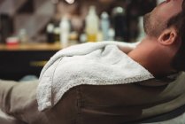 Primo piano del cliente che si rilassa sulla sedia in barbiere — Foto stock