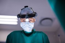 Female surgeon wearing surgical loupes while performing operation in operation theater — Stock Photo