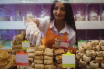 Mujer tendero arreglando dulces turcos en el mostrador en la tienda - foto de stock