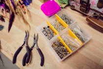 Close-up of pliers and beads on desk in shop — Stock Photo