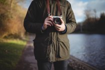 Mid-section of man holding camera outdoors — Stock Photo
