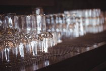 Primer plano de los vasos vacíos dispuestos en un estante en un bar - foto de stock