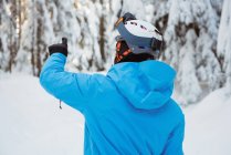 Rückansicht des Skifahrers, der auf eine verschneite Landschaft zeigt — Stockfoto