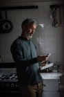 Mann benutzt Handy in Küche zu Hause — Stockfoto