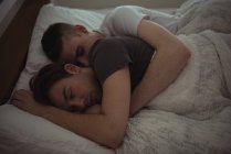 Gay casal abraçando enquanto dormir no cama no quarto — Fotografia de Stock