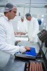 Butchers weighing packages of minced meat at meat factory — Stock Photo