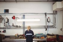 Vista trasera de la mecánica femenina trabajando en garaje de reparación - foto de stock